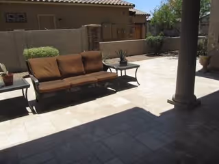 Outdoor patio with brown cushioned seating, small tables, and potted plants.