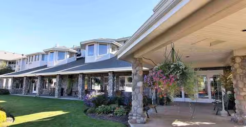 Exterior view of Stone Lodge Gracious Retirement Living with stone pillars and hanging planters