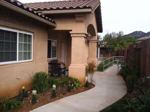 Sapphire Pacific exterior shows a walkway, bench seating, and landscaped plants near the entrance.