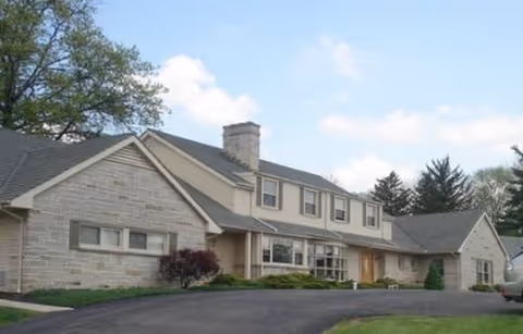 Exterior view of a stone-faced senior living facility with a driveway.