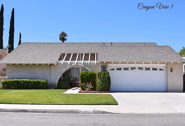 Single-story beige residential home with a two-car garage and manicured front lawn.