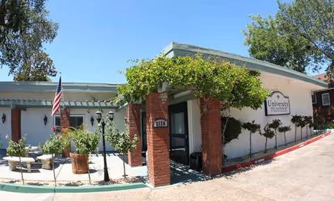 Exterior view of University Post-Acute Rehab facility with entrance, vines, flag, and landscaping.