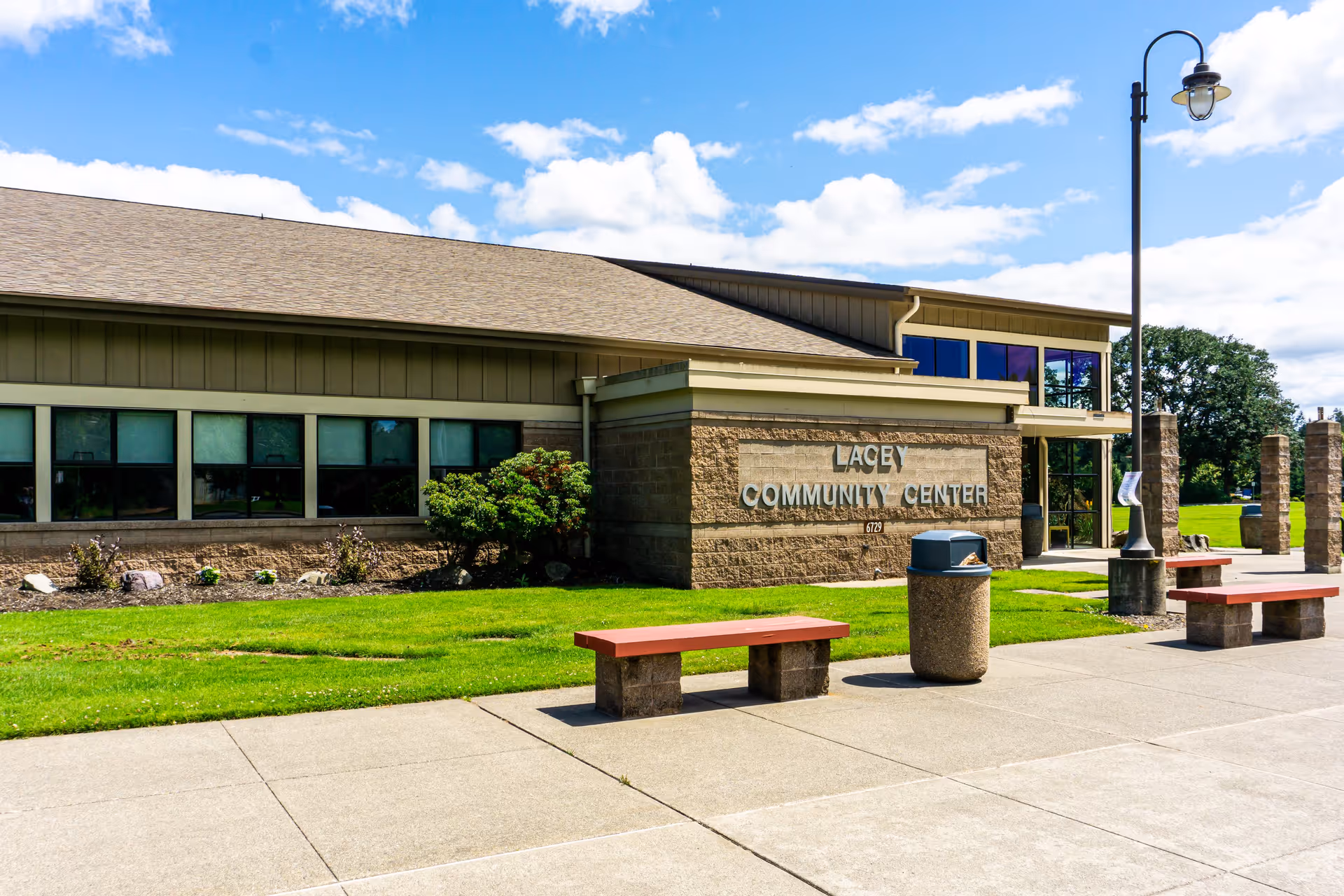 Exterior front of a community center building with benches, a lamp post, and a sign reading "LACEY COMMUNITY CENTER".