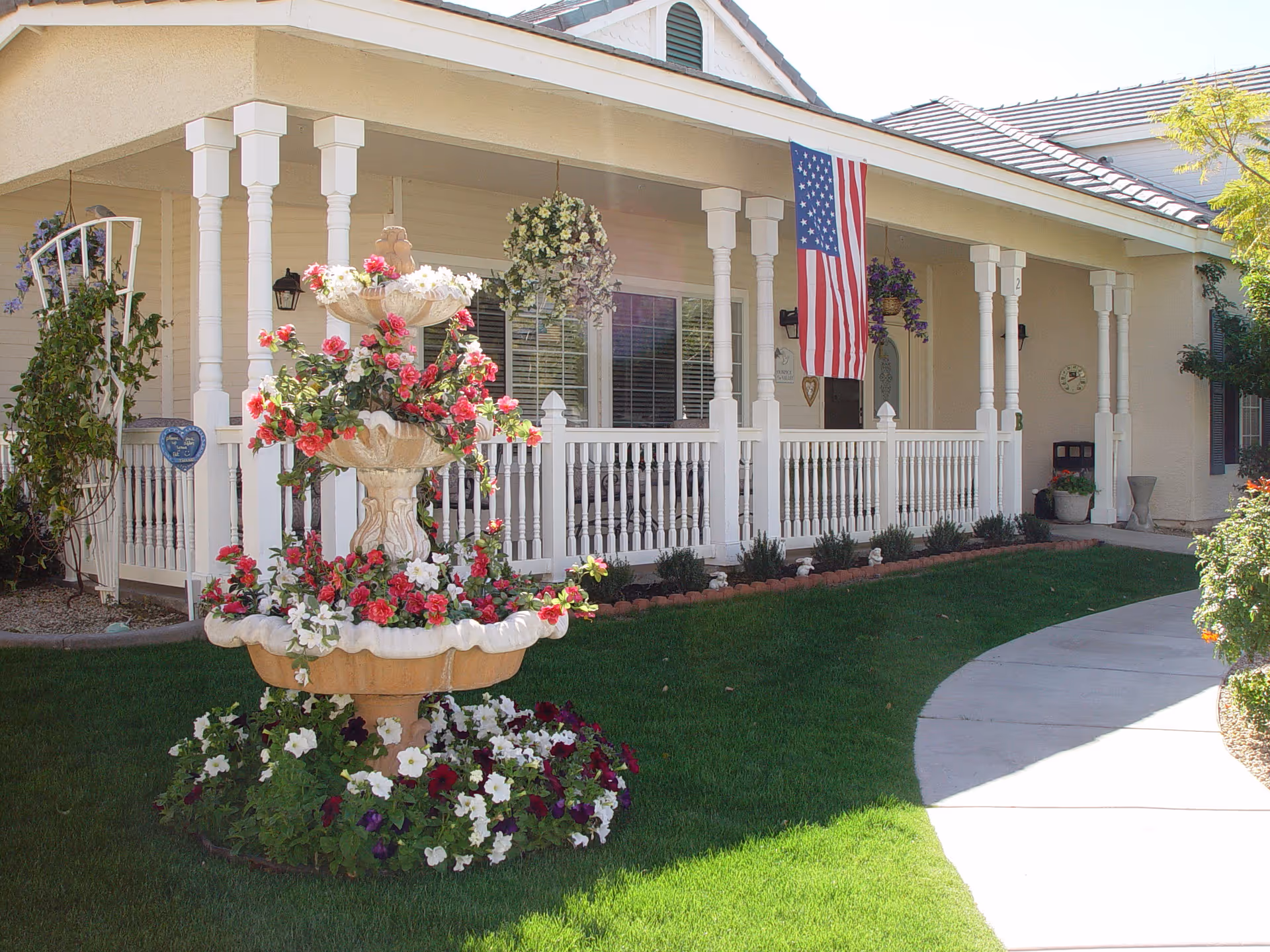 Front view of Arbor Rose Senior Care with white porch, fountain, and hanging flower baskets.