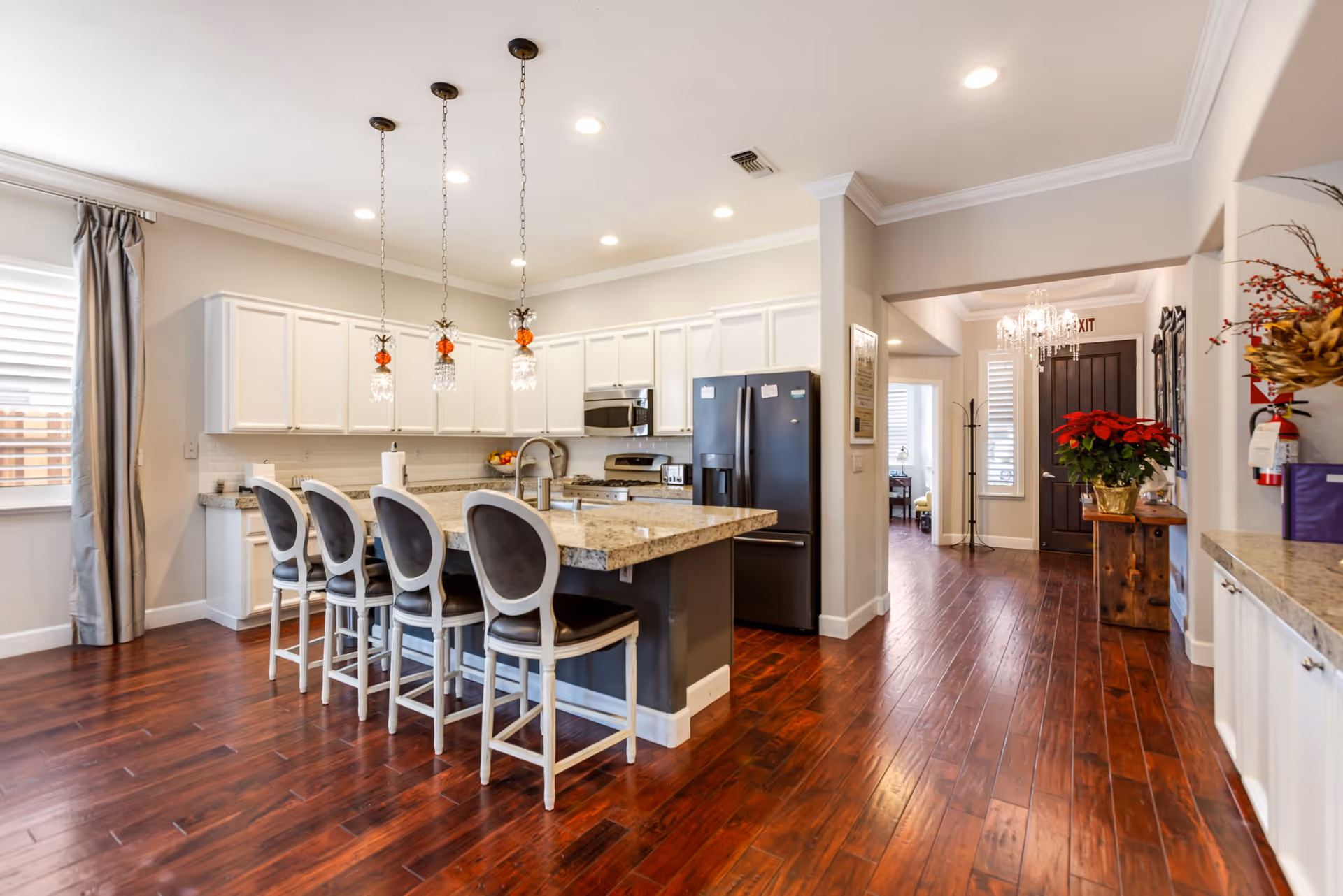 A modern kitchen with a granite countertop and bar seating in a senior living facility.