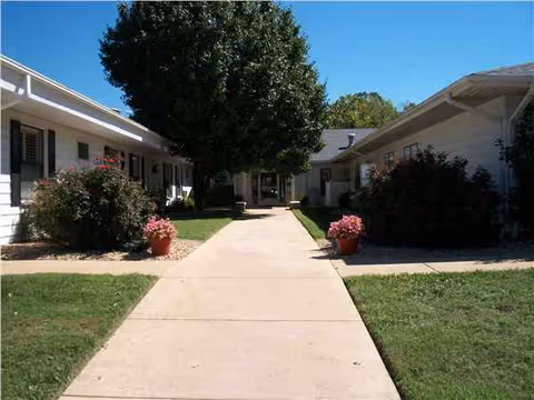 Rocky Ridge Manor exterior with a central walkway, lawns, shrubs, and a large tree.