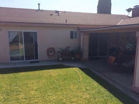 Backyard patio of a senior living facility featuring a sliding door, lawn, and seating.