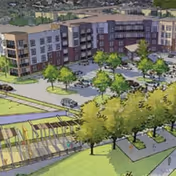 Aerial view of a multi-story senior living facility named Watermere at Woodland Lakes, showing the building surrounded by parking spaces, trees, and landscaped outdoor areas including a pergola and walking paths.