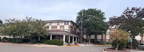 Exterior view of Oak Ridge Manor, a two-story brick senior living facility with a covered entrance and surrounding trees.