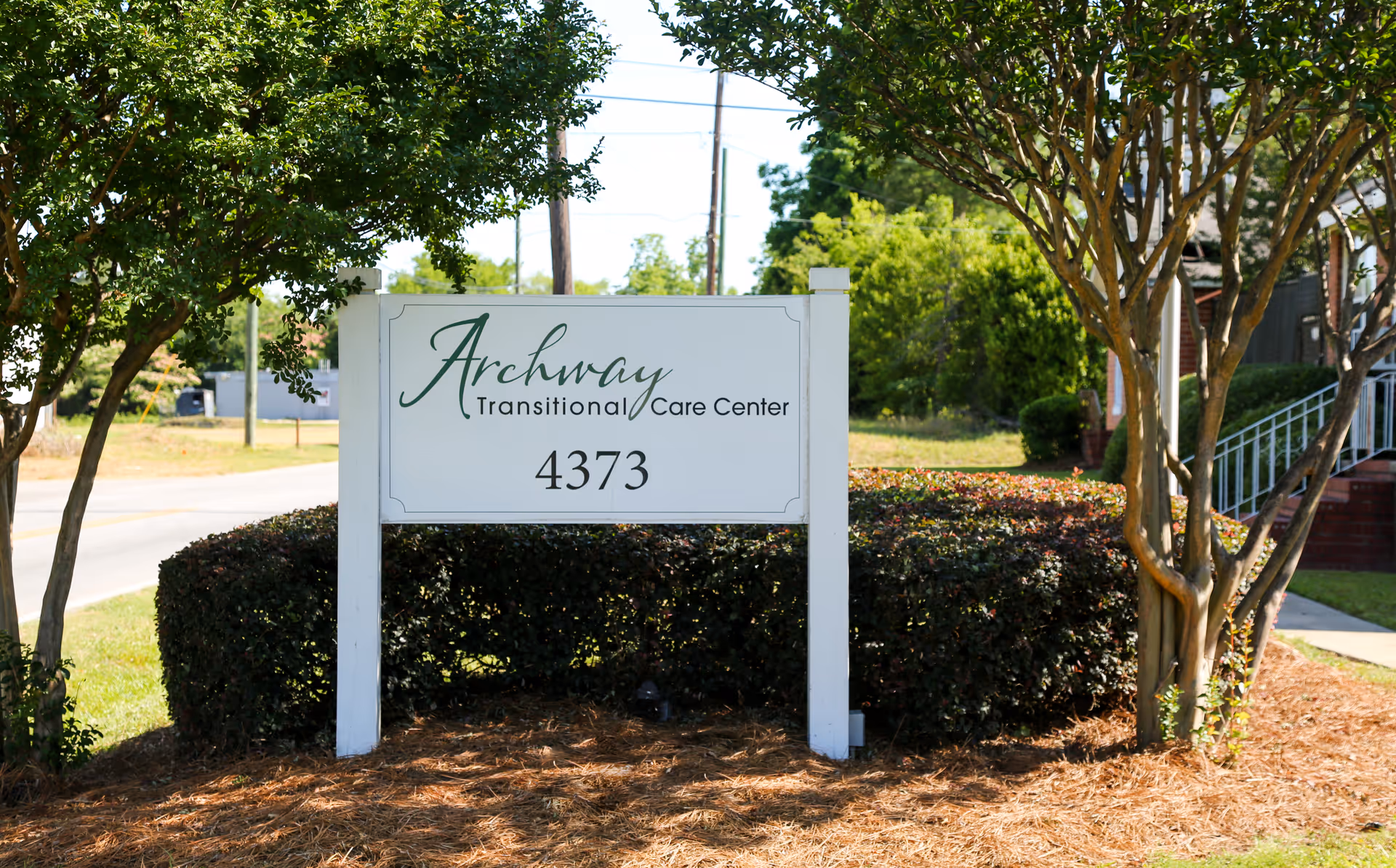 Sign for Archway Transitional Care Center prominently displayed with greenery in the background.