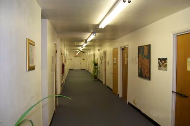 Long, well-lit interior hallway at Wood Living Center of Quanah with doors along both walls.
