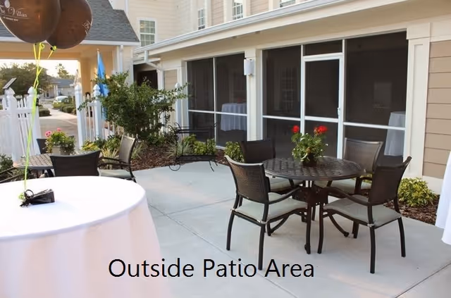 Outdoor patio with round tables, chairs, and potted plants beside a residential building.
