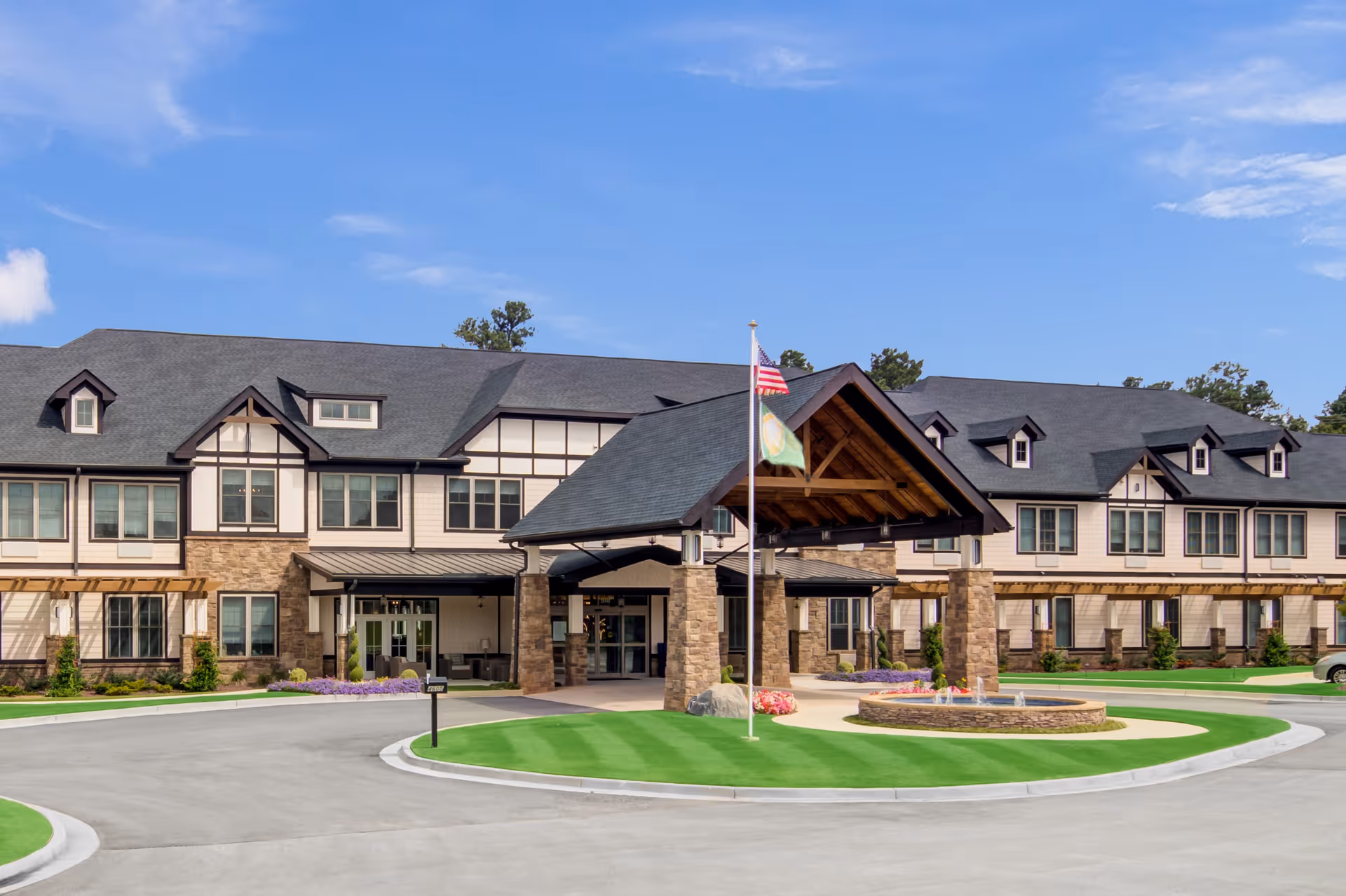 Exterior view of Oaks at Douglasville facility with circular driveway and flag at entrance.