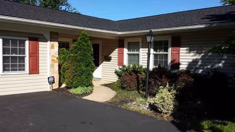 A single-story assisted living home exterior with a walkway, landscaping, and entrance.