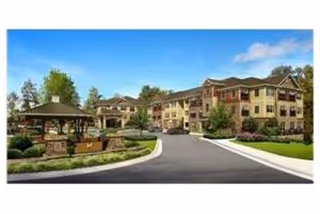 Front entrance and driveway of a multi-story senior living building with landscaped grounds and a gazebo.