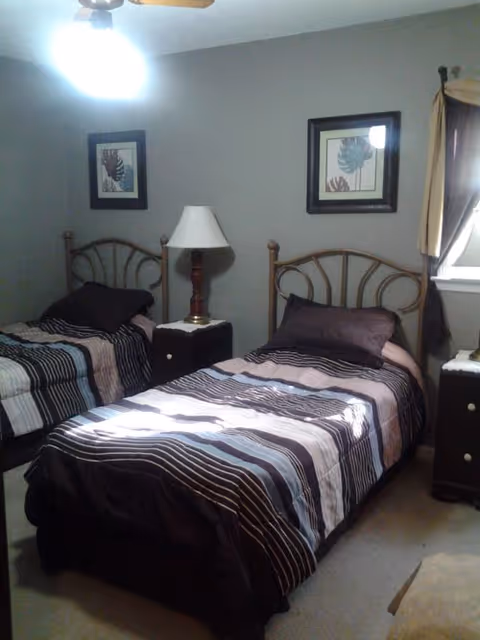 Two twin beds in a shared bedroom with nightstands and framed wall art.
