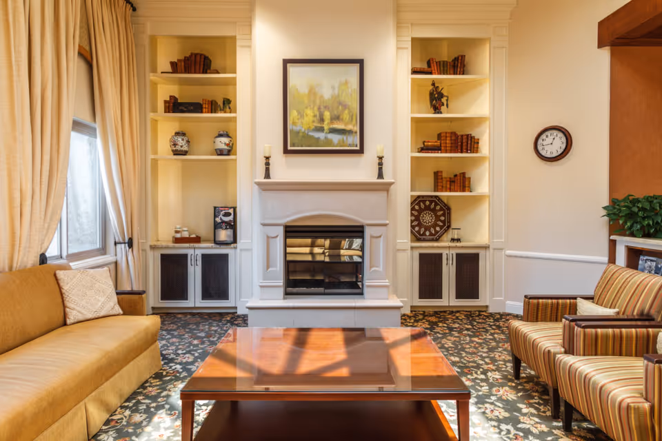 Comfortable living room with a central fireplace flanked by built-in shelves, sofas and a wooden coffee table on a patterned rug.