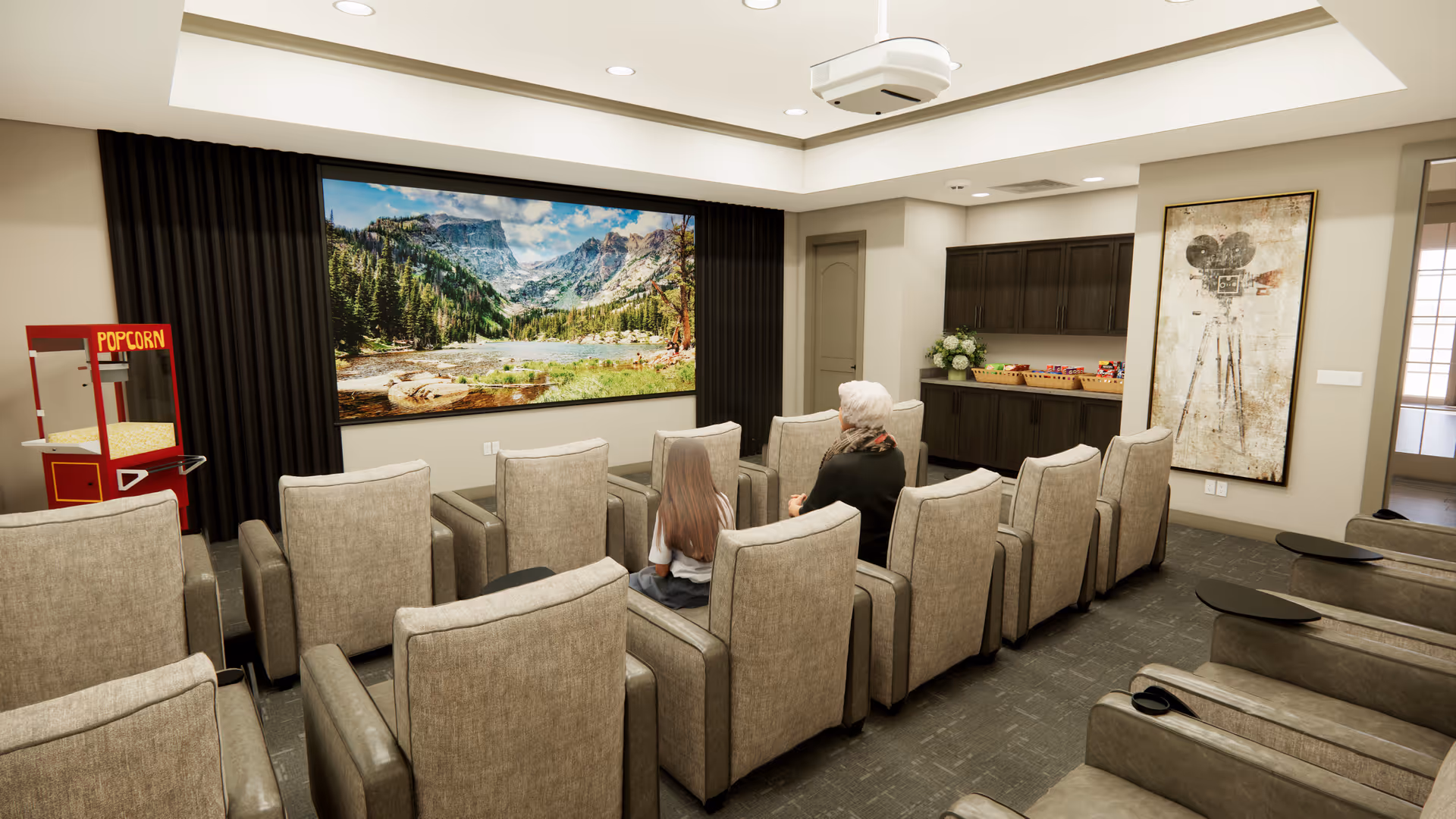 A cozy senior living facility movie room with two people seated in comfortable beige armchairs facing a large screen displaying a scenic mountain and forest landscape. There is a popcorn machine on the left side and a cabinet with snacks on the right side, along with a vintage movie camera artwork on the wall.