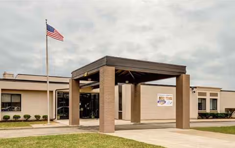 Exterior view of Oak Creek Terrace Nursing and Rehab Center entrance with canopy and American flag.