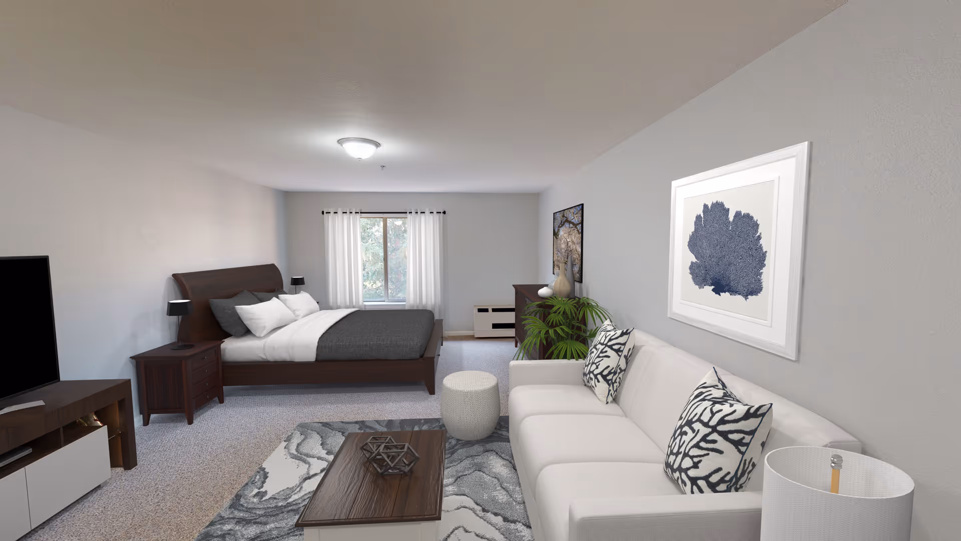 Open studio-style living area with a white sofa and coffee table in the foreground and a bed with nightstands in the background.