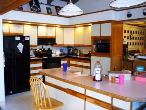A kitchen with a central island, wooden cabinets, and appliances in a senior living facility.