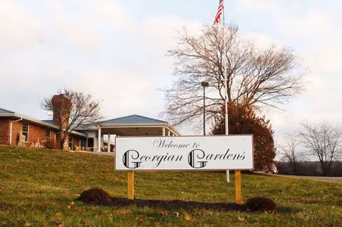 Front view of Georgian Gardens Care Center exterior with a welcome sign on a grassy lawn.