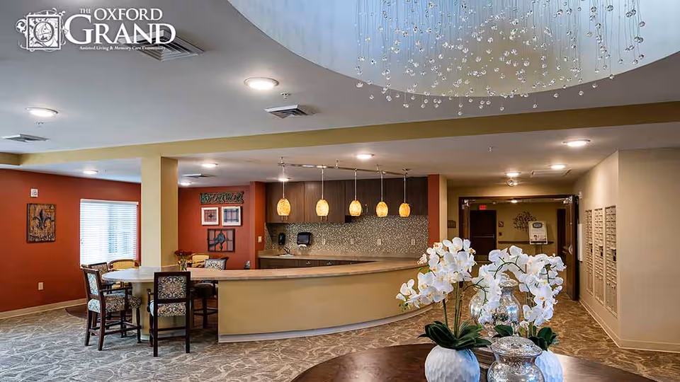 Open reception/lounge area with a curved front desk, pendant lights, seating, and a floral centerpiece on a table.