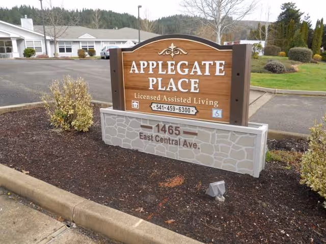 Wooden sign for Applegate Place outside a licensed assisted living facility.