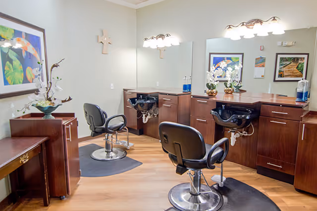 Salon area with two styling chairs, shampoo basins, large mirrors and wooden cabinetry.