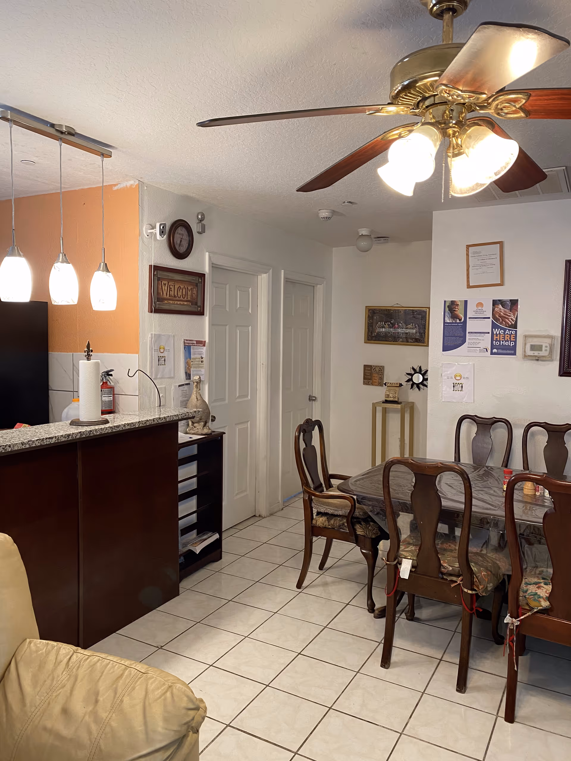 Dining area and kitchen counter with a wooden dining table and chairs, pendant lights, and a ceiling fan.