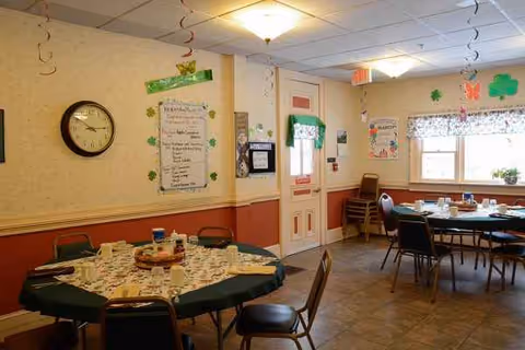 Interior dining room with round tables set for a meal and wall decorations.