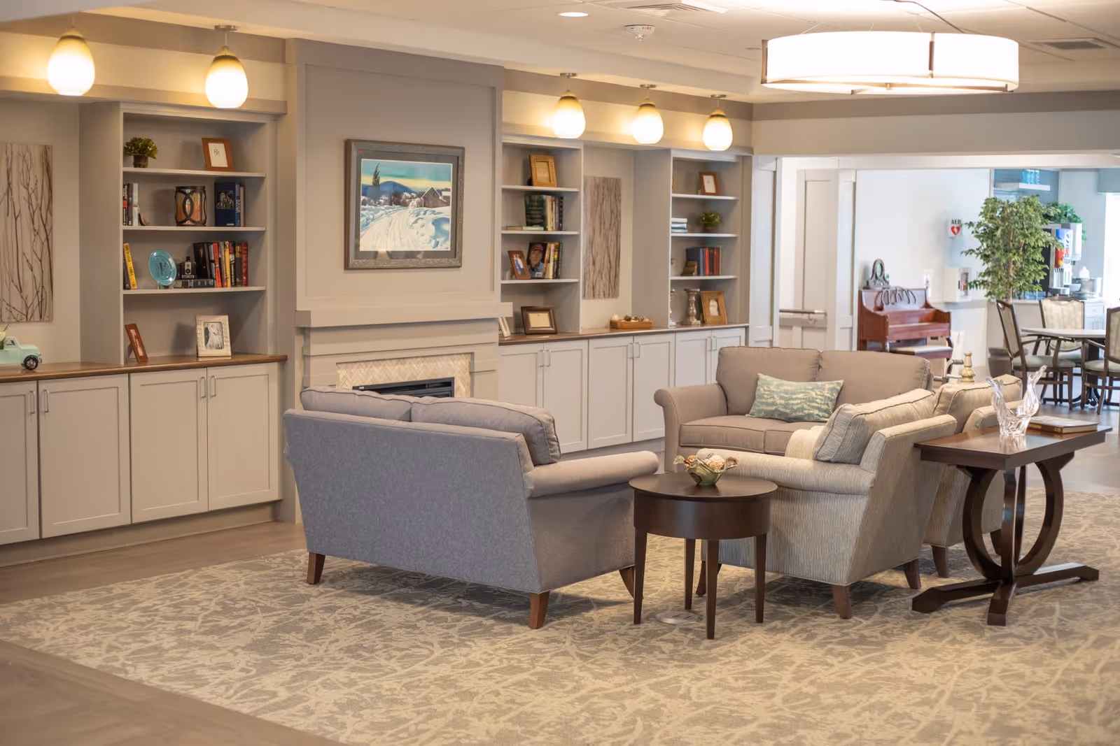 Cozy communal living room with sofas arranged around a fireplace and built-in bookshelves.