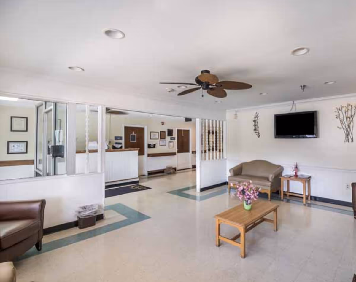 Bright reception lobby with seating, coffee table, TV, and a reception desk.