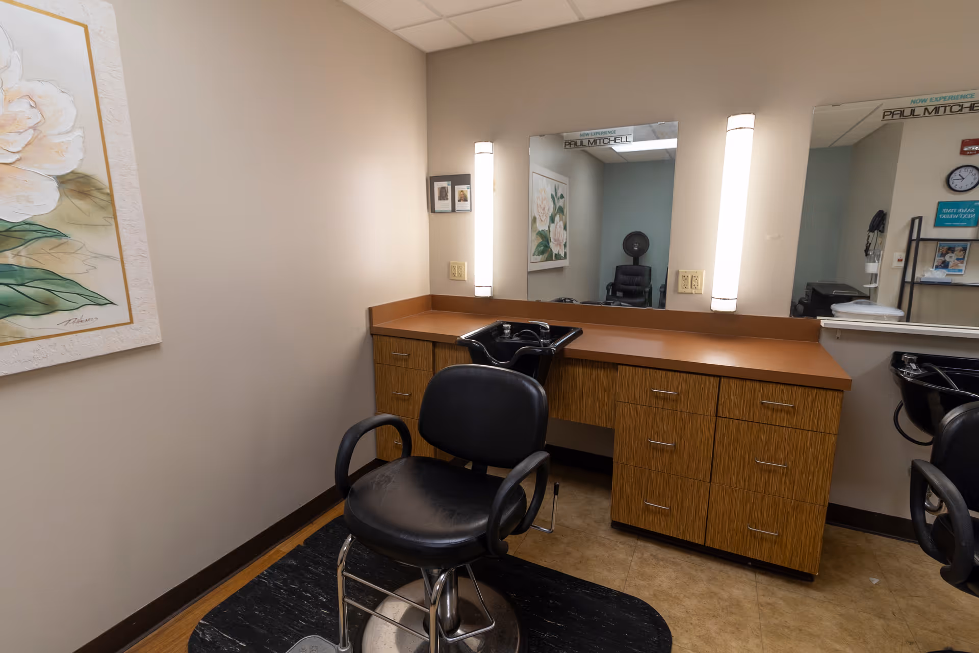 Salon-style hairdressing station with styling chairs, wash basins, mirrors, and cabinetry.