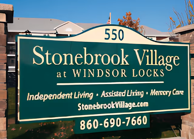 Green entrance sign reading "Stonebrook Village at Windsor Locks" with the address number 550 and phone number 860-690-7660.