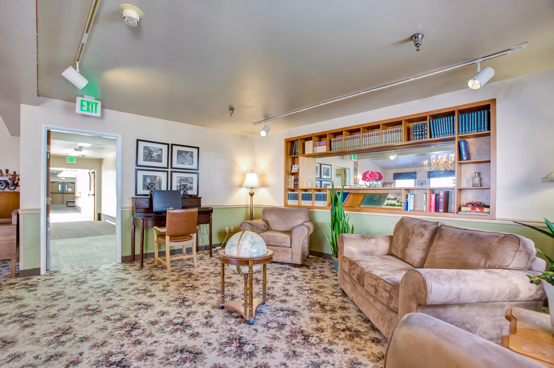 Cozy common living room with sofas, armchairs, a bookshelf, a desk and a globe table.
