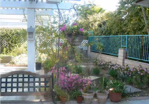 Outdoor garden area with potted plants, bench, and metal railing at Golden Age Senior Homes.