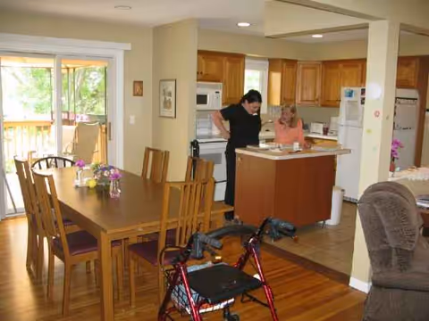 Open-concept dining and kitchen area with two women near the island, walker present.