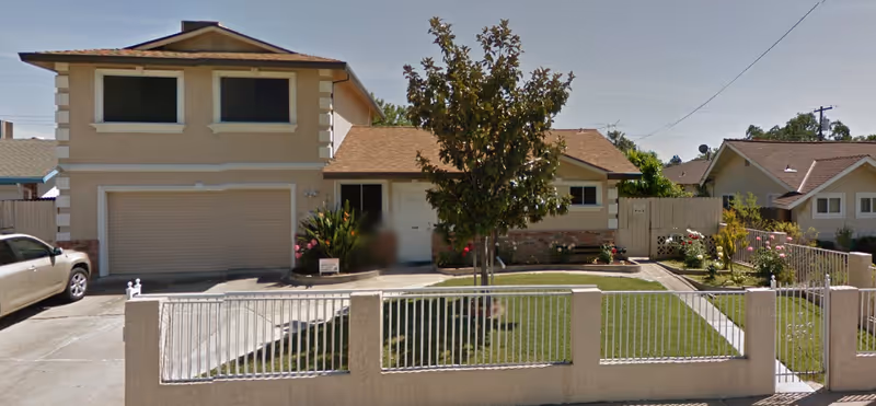 Front view of Candlelight Home Care RCFE LLC building with gate and lawn.