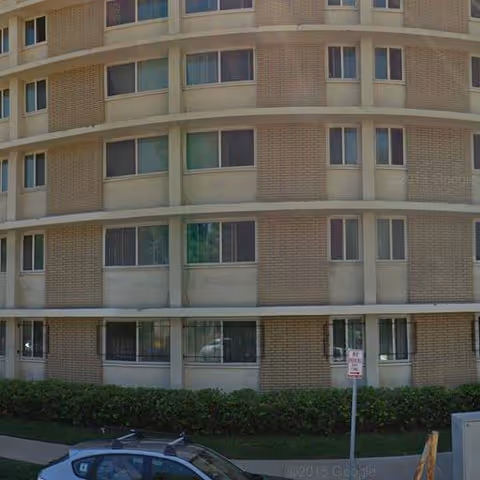 Multi-story brick senior living facility facade with windows and a parked car.