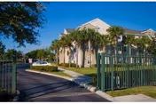 Front view of Windsor Park Apartments with palm trees and a green gate