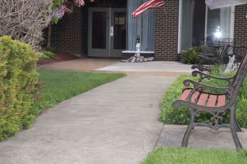 Exterior view of Dunkirk Rehabilitation and Nursing Center entrance with benches along walkway.
