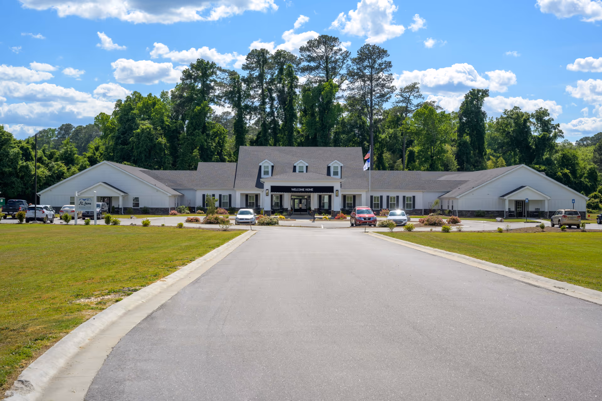 Exterior view of At Home Senior Living of Thomson facility surrounded by green landscaping.