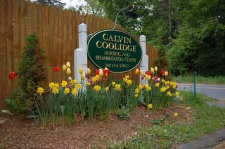 A Calvin College Nursing and Rehabilitation Center sign stands beside colorful tulips.