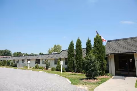 Exterior view of Ridgewood Rehabilitation and Living Center, a single-story building with shrubs and parking.