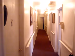 Narrow hallway inside a senior living facility lined with doors on both sides