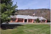 Exterior view of a single-story brick senior living facility with a flag.