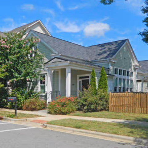 Light-blue elder care facility exterior with front entrance and landscaped garden.