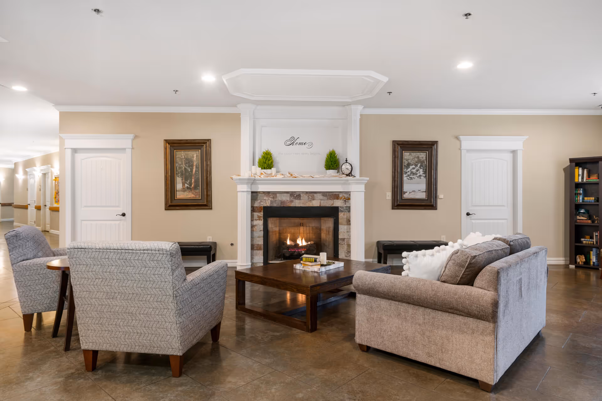 Cozy communal living room with sofas and armchairs arranged around a coffee table and a lit fireplace.