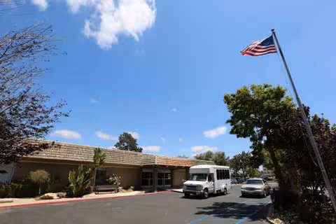 Exterior view of Santa Maria Terrace with a flag, trees, and a shuttle van.
